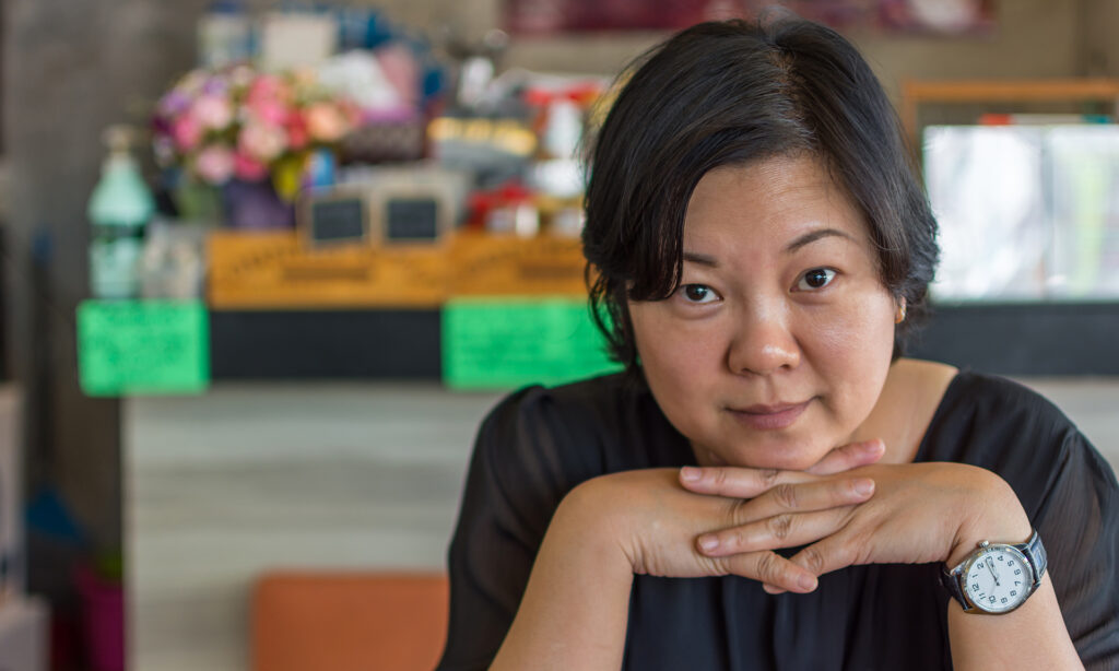 women in black dress rests her chin on her hands in a coffee shop cafe