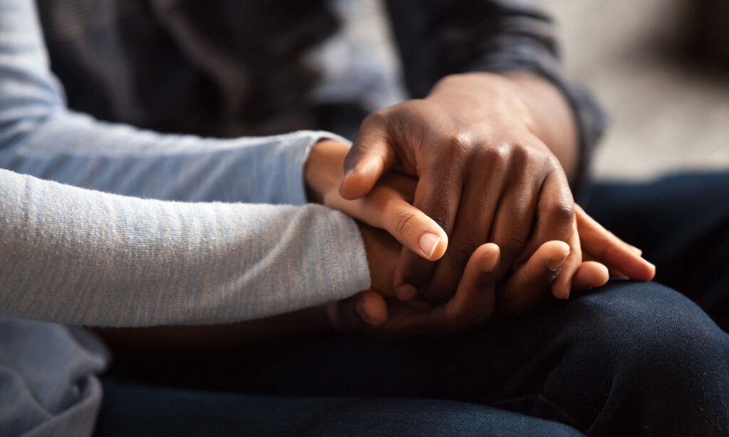 Close up of two peoples hands being held together supportively