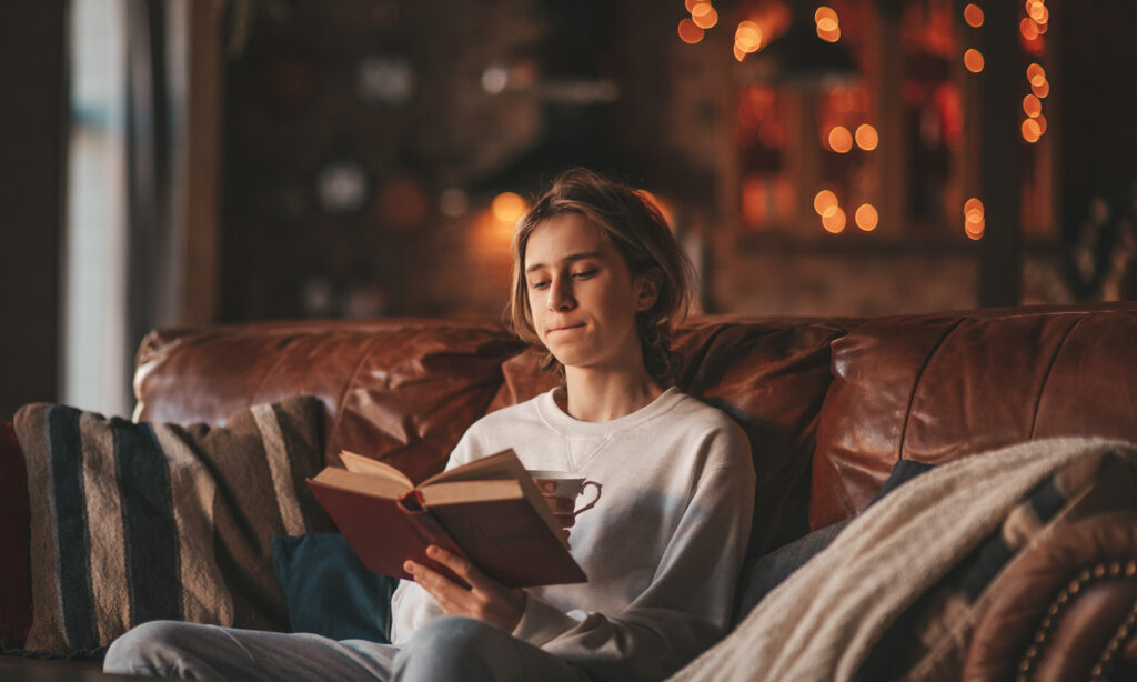 Young teen boy with long hair holding and reading study book