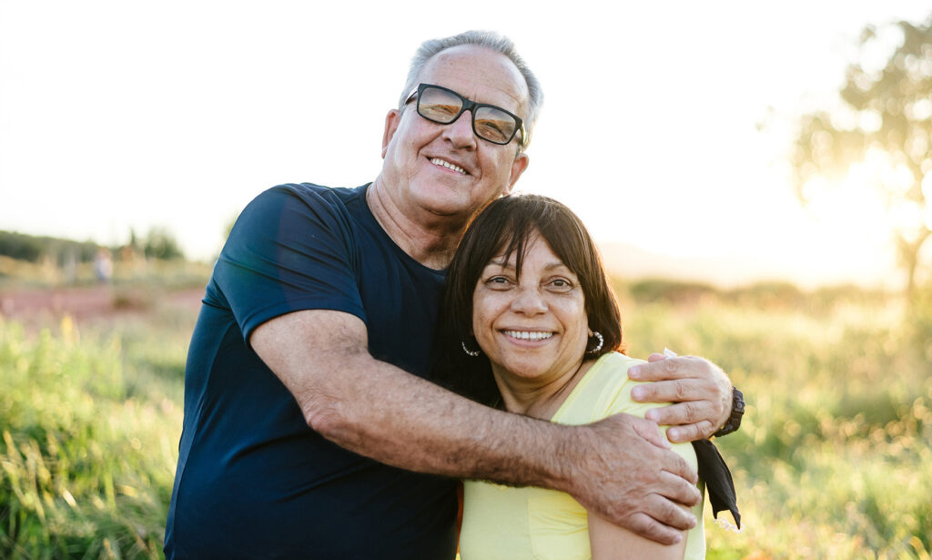 An older couple hugging in a rural setting at sunset