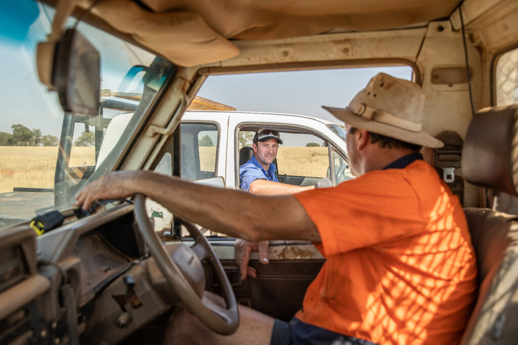 Men talking to each other while stopped in their utes on the farm