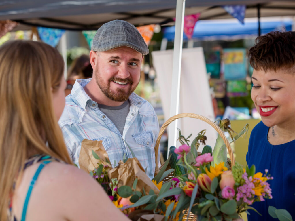 Three people at a market looking at flowers