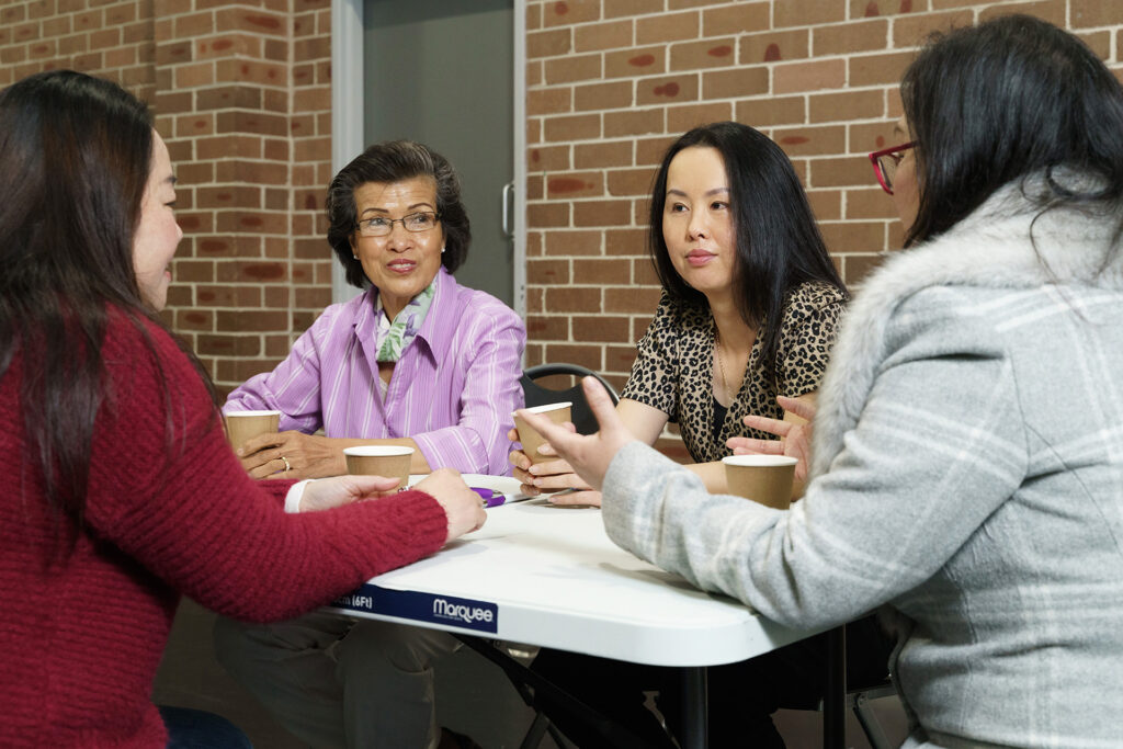 A group of people sitting around a table in front of brick wall.