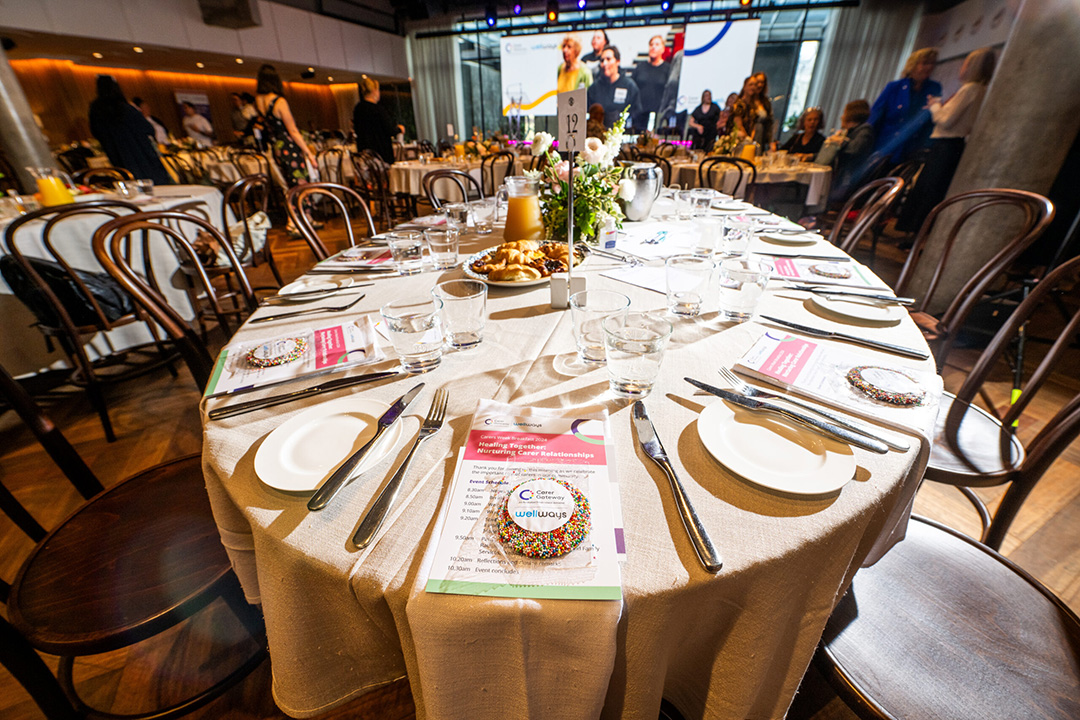 A table nicely made with, flowers, silverware, white plates and a cookie covered in coloured sprinkles.