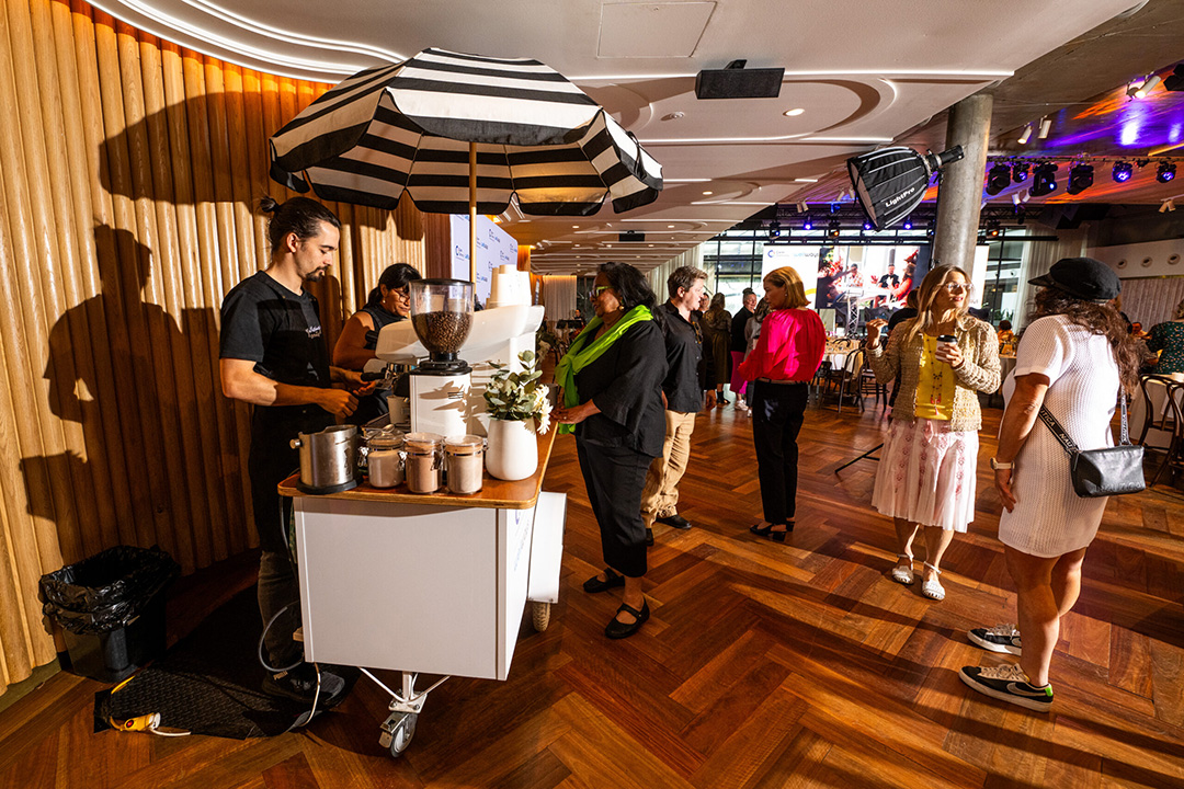 A coffee cart serving a line of people in a conference room.