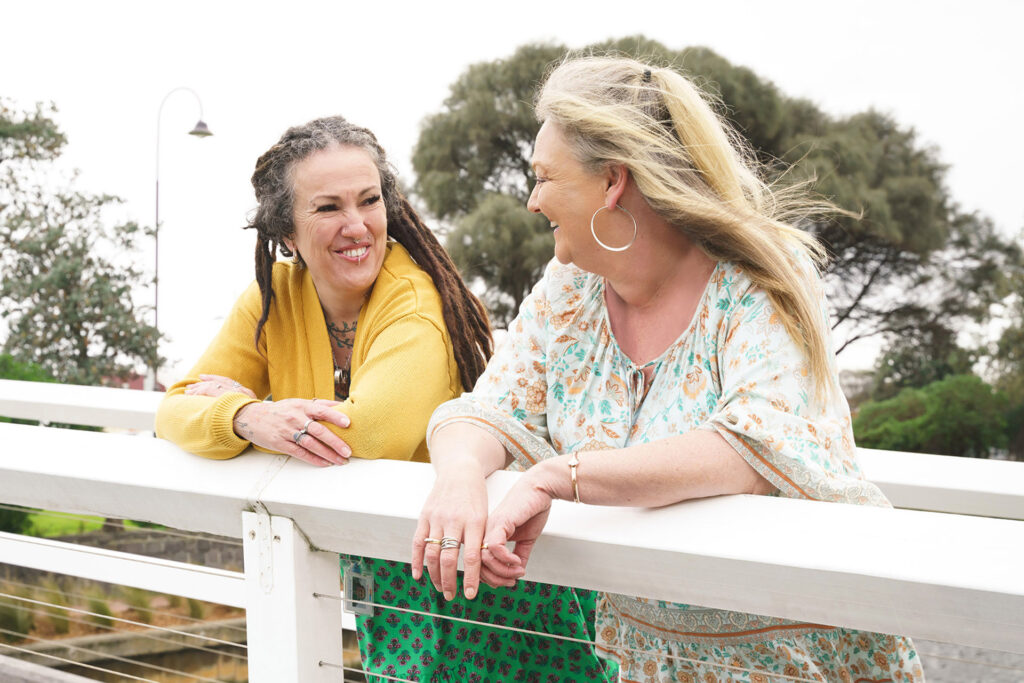 Two people speaking happily on a footbridge