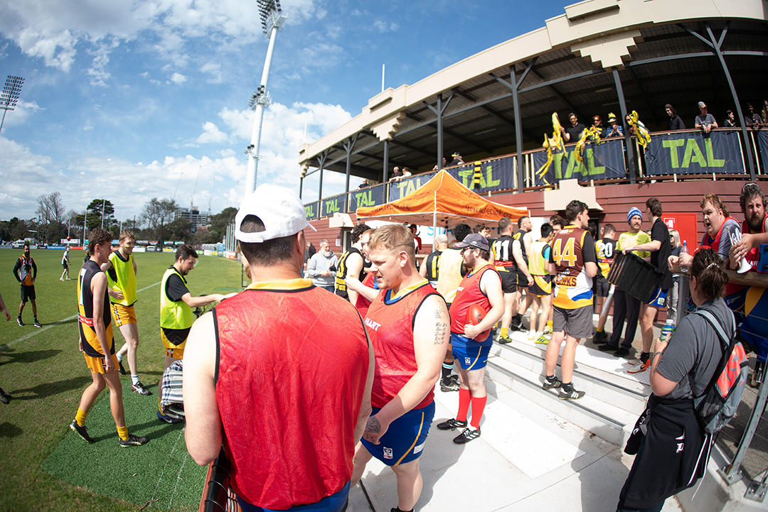 A group of football players next to the grand stand on a field getting ready to play