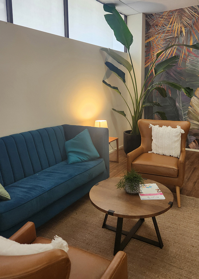 A blue couch with two brown leather side chairs and a centre table.