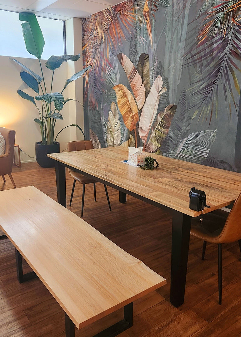 A nicely decorated table space in a room with a colourful mural on the wall and natural lighting. 