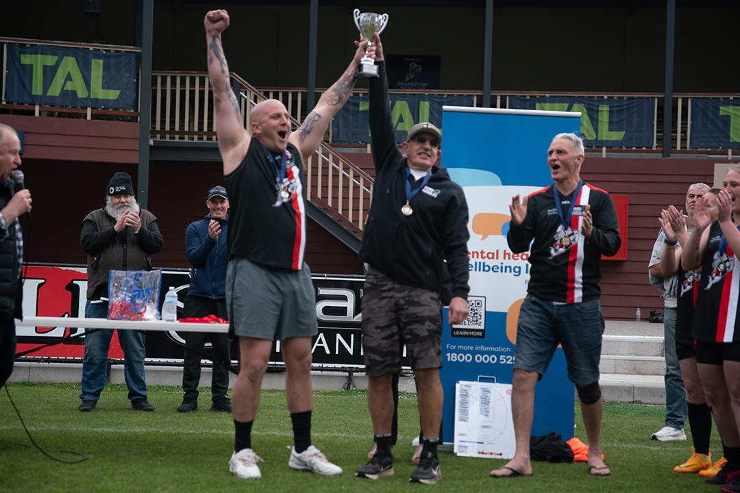 A footballer and another man holding a trophy in the air