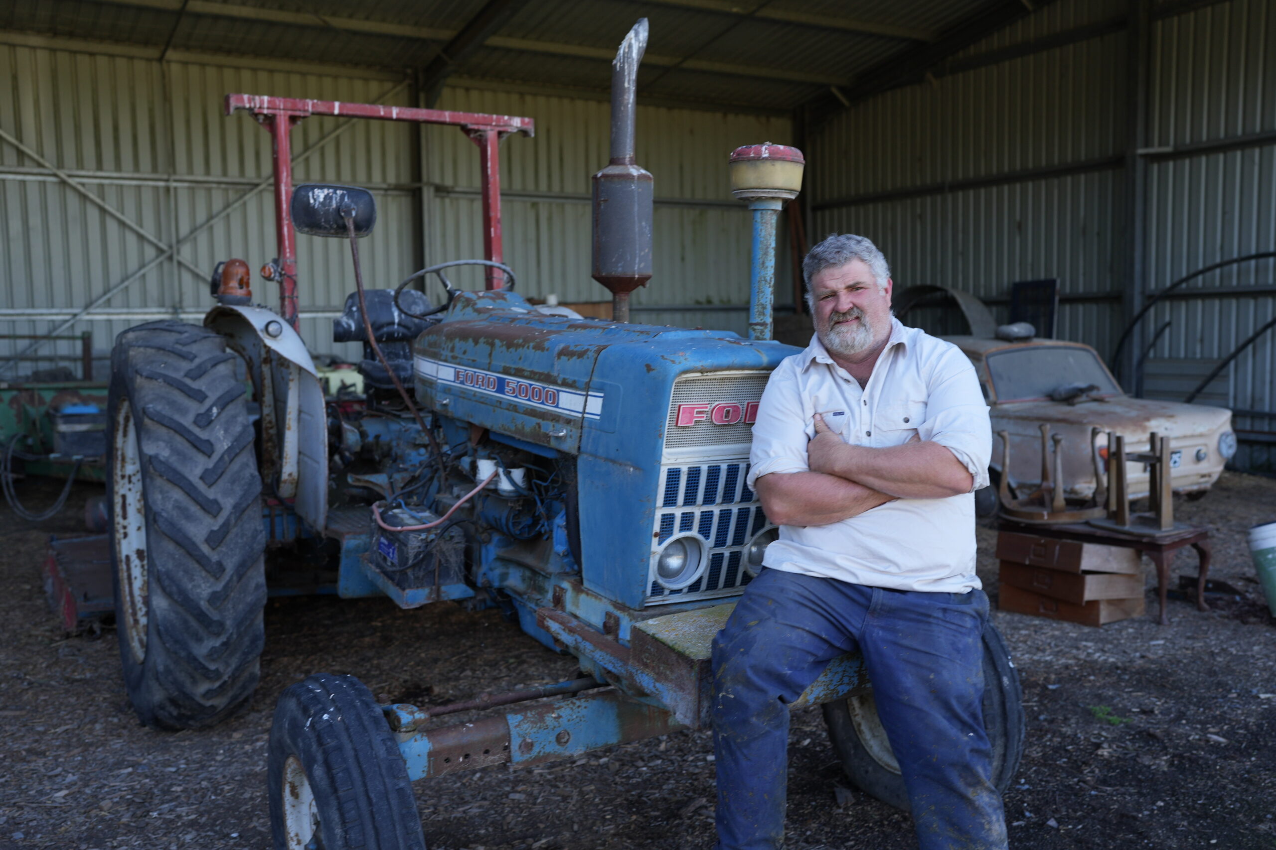 A person sits on an old blue tractor.