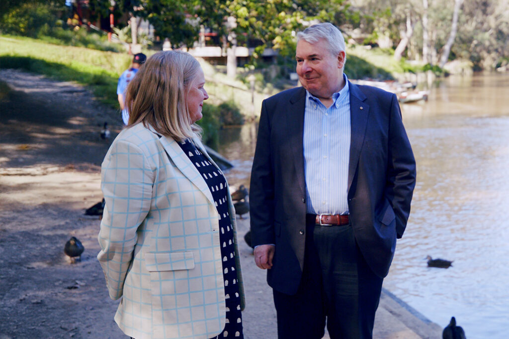 Wellways CEO Laura Collister and Board Chair Michael Gorton stand beside the Yarra River in Fairfield, surrounded by ducks.